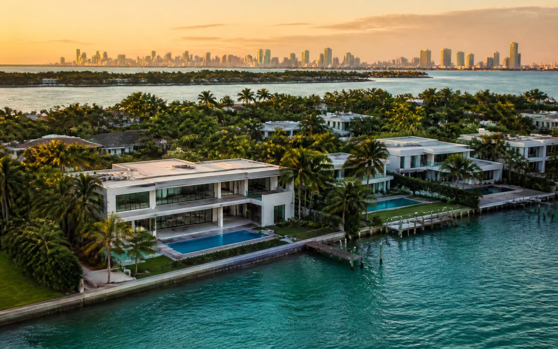 Aerial view of luxury South Florida waterfront estates with Miami skyline at golden hour
